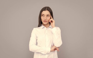İş başarısı. İş kıyafetleri içinde başarılı bir kadın. Gri arka planda yönetici yönetici. Kadın resmi modası. Kendine güvenen bayan patron. Düşünen beyaz gömlekli bir iş kadını.