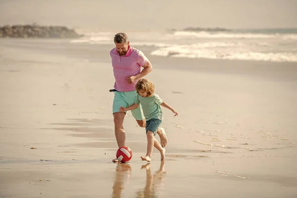 father and son play football have fun on summer beach with ball, childhood.