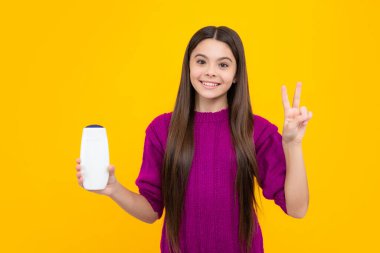 Şampuan kremi ve duş jeli olan genç bir kız. Genç kızın uzun saçı. Kozmetik ürünler, şampuan şişesi. Saçlarını şampuanlıyordum.