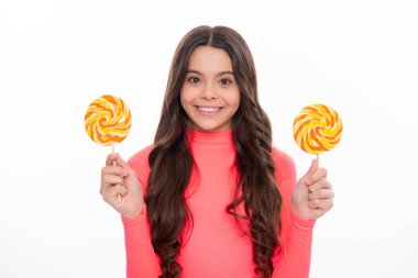 Şekerli lolipop yiyen genç bir kız. Çocuklar için şeker ve şeker. Çocuk beyaz izole arka planda lolipop yiyor. Lezzetli karamel, şekerci dükkanı. Mutlu kız yüzü