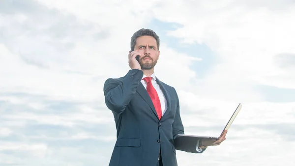 businessman in suit talk on phone and hold laptop.