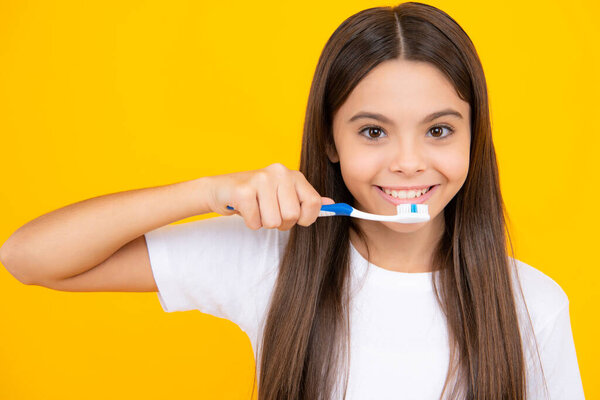 Happy teenager portrait closeup. Funny teen girl brush her teeth, dental healthy concept, isolated over yellow background. Healthy kids teeth. Oral medical and stomatology concept. Smiling girl