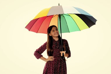 Şık bir ergen kız. Mutlu çocuk renkli şemsiye tutar. Gökkuşağı şemsiyeli çocuk beyazın üstüne izole edilmiş. Sonbahar sezonu. Yağmurlu hava tahmini. Okula dönüyorum. sonbahar moda aksesuarı.