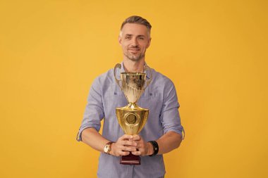 İş başarısının motivasyonu. Ödül ve prestij. Ödül aldım. Adam zaferi kutluyor. İlham ve motivasyon. Gülümseyen olgun adam altın kupayı tutuyor. başarı ödülü.