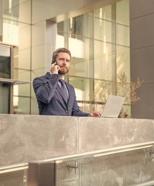 Çevik iş. İş adamı blog yazmak için dizüstü bilgisayar kullanıyor. İş iletişimi ve akıllı telefondan konuşma. Pazarlık. Modern bilgisayar teknolojisi. e-postayı kontrol et Serbest Adam blogu çevrimiçi.