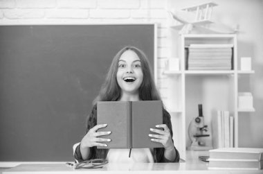 Şaşırmış çocuk ödevlerini kitapla yapıyor. Genç bir öğrenci. Modern eğitim. Lisede. Kitapçığı olan liseli kız. Çocuk not defteri okuyor. Okula dönüyorum. Genç kız çalışmaya hazır..