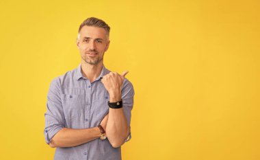 Beyaz saçlı, gülümseyen olgun bir adam sarı arka planda baş parmağını göster, kopyala, işaret et..