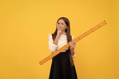 Ölçme ve ölçme. Çocuk eğitimi. Matematik. Düşünen genç kız cetvel tutuyor. Okula dönüyorum. Cebir ve geometri. Matematik dersi alan bir çocuk. Boyutunu ölçün. trigonometri sayfası.