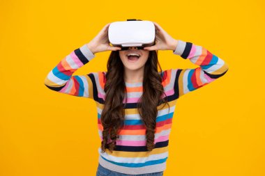 Şaşırmış bir genç. Çocuklar için sanal aletler, boş zaman ve eğitim. Genç kız sarı arka planda izole edilmiş VR gözlükleri kullanıyor. Heyecanlı genç kız