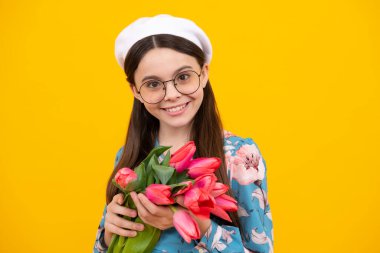 Bereli mutlu genç kız sarı arka planda bahar lale çiçekleri tutuyor. Bahar laleli çocuk buketi, çiçekli hediye