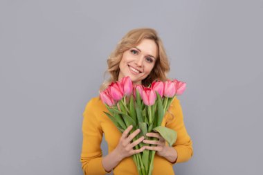 Laleli neşeli bir kadın. Bayan bahar tatili için çiçekleri saklar. Gri arka planda buketi olan kız. Kadınlar günü için çiçek hediyeleri. 8 Mart ve Anneler Günü.