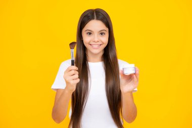 12, 13, 14 yaşlarında pudra ve fırçayla güzellik yapan bir kız çocuğu. Makyaj yapan güzel bir genç. Mutlu ergen portresi. Gülümseyen kız