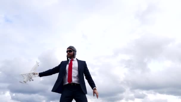 スーツパイロットの帽子と眼鏡を身に着けて空を背景に飛行機で踊るビジネスマンビジネス専門家 — ストック動画