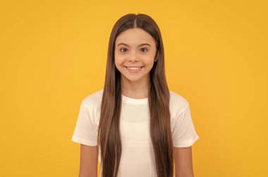 Uzun saçlı neşeli bir çocuk. Güzellik ve moda. Kadın manken. Genç bir kızın güzel görünüşü. Sarı arka planda mutlu çocuk portresi. pozitif duyguları ifade et.