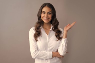 Formalite bölümündeki mutlu profesyonel kadın menajer, ürün sunan, fotokopi alanı gri arkaplanı için elini açık tutuyor..