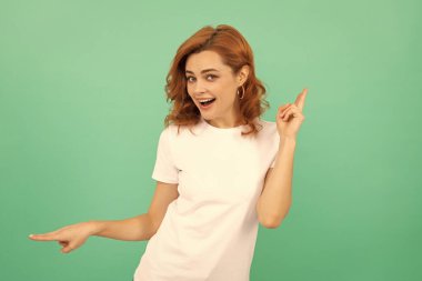 Kıvırcık saçlı mutlu kızıl kız mavi arka planda barış jestleri gösteriyor, pozitiflik.