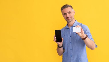 Kredi kartı ya da banka kartı. Adam internet bankacılığı ile ödeme yapıyor. Alışveriş uygulaması. Siber pazartesi. Hızlı ödeme. Neşeli adam akıllı telefon gösterdi. Müşteri internet parasını cep telefonunda kullanıyor. gösterim kartviziti.