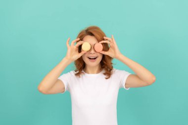 Komik kız, mavi arka planda tatlı Fransız kurabiyesi tut..