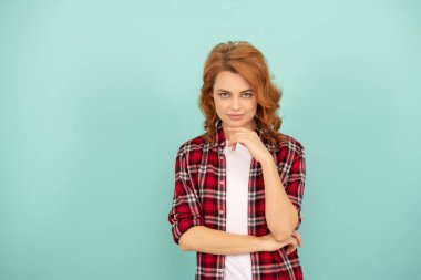 Mavi arka planda kareli gömlekli, kızıl saçlı, çapkın bir kadın..