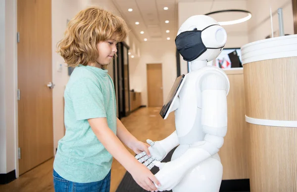 Küçük çocuk robotla yenilikçi teknoloji ve iletişim gibi etkileşim içinde..