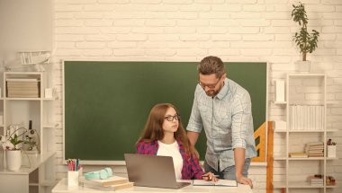 Meraklı çocuk ve baba, bilgisayar başında karatahta ve çocuklukta sınıfta otururlar..