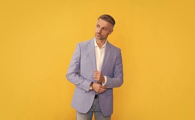 Yetişkin bir iş adamı. İş başarısı. Takım elbiseli başarılı bir adam. Sarı arka planda yönetici yönetici. Erkek resmi moda. Kendine güvenen sakallı patron.