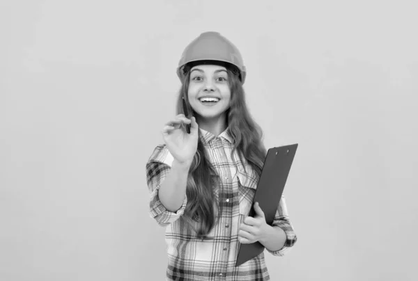 快乐的少女 戴着头盔 穿着格子衬衫 在剪贴板上记笔记 童年时代 — 图库照片
