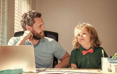 Bilgisayarda online eğitim. Evde eğitim ve para kazanmak. Okula dönüyorum. Gülümseyen baba ve oğul evde iletişim teknolojisi kullanıyor. Aile blogu. Çocuk öğretmenle ödev yapıyor. webinar video dersi.