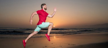 Günbatımı plajında koşan atletik adam, meydan okuma. Koşan ve zıplayan adam, kopyalama alanı olan pankart