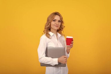 Dizüstü bilgisayarı olan profesyonel iş kadını hazır kahve ya da çay fincanı sarısı arka planda, kır..