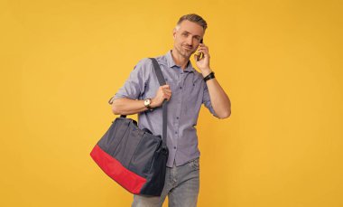 Telefon görüşmeleri. mobil teknoloji gibi ses teması. Cep telefonundan konuş. İletişim. Gülümseyen iş adamı akıllı telefonda seyahat çantasıyla konuşuyor. Adamın sohbet çantası var..