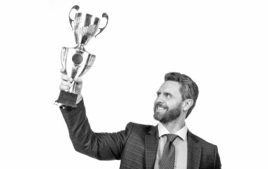 Takım elbiseli başarılı bir işadamı şampiyon kupasını beyaz tenli, başarılı bir iş adamı olarak elinde tutuyor..