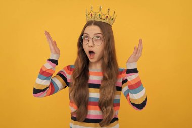 Şaşırmış egoist gözlüklü çocuk sarı arka planda kraliçe tacı takıyor. Sürpriz..