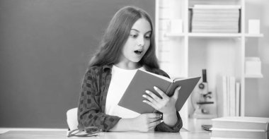 Şaşırmış genç öğrenci. Modern eğitim. Lisede. Kitapçığı olan liseli kız. Çocuk defter okuyor. Okula dönüyorum. Genç kız çalışmaya hazır. Çocuk ödevlerini kitapla yapıyor..