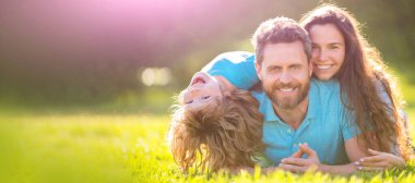 Anne, baba ve oğul birlikte rahatlayın. Evlat edinme ve sadaka. Aile günü. Arkadaşlık. Baba ve çocuk yeşil parkın çimlerinde. Arkadaş canlısı aile yazın eğleniyor. gülümseyen ebeveynler ve çocuk.