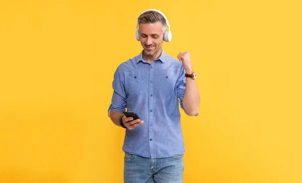 modern life and lifestyle. guy chatting in earphones. musical playlist. mobile music application. new app. happy guy in headphones use smartphone. successful man listen music and hold phone.
