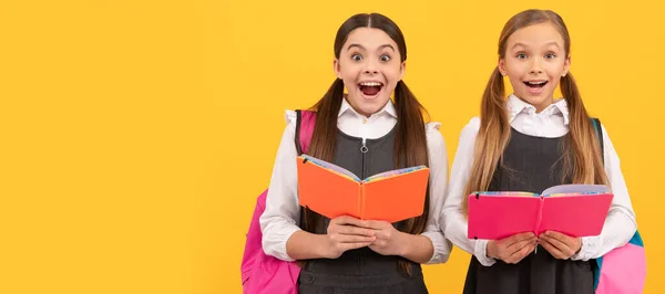 学校女生朋友 穿着正式校服的孩子们很惊讶地看到了学校的书 黄色背景的书 图书馆 学校女学生横幅 带有复制空间的女学生肖像 — 图库照片