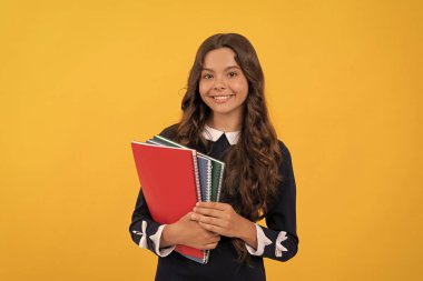 gülümseyen çocuk okul defterlerini tut ev ödevleri için sarı arka plan ve eğitim üzerine çalış.