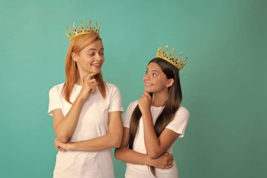 Kibirli kadın anne ve kızı birbirlerine gülümsüyorlar. Mavi taçlı, bencil..