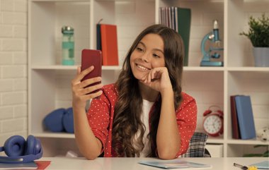 Gülümseyen çocuk video blogu yapıyor. Telefonla blog yazıyorum. Cep telefonlu vlogger 'ın güzel bir gülümsemesi var. Genç kız blogcu akıllı telefon kullanıyor. Okula dönüyorum. Çocuk sınıfta selfie çekiyor. Eylül 1.