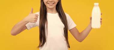 Mutlu çocuklar süt ürünleri bulundurur. Genç kız süt içecek. Sağlıklı bir yaşam tarzı. Çocukluk gıdası. Günde bir içki. Süt ürünleri. Kahvaltıda yoğurt. Çocuk süt şişesini tutuyor. başparmak yukarı.