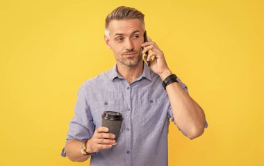 Kahve içen hayret bir adam. Modern hayat ve yaşam tarzı. Adam paket çay içiyor. Günaydın. İletişim. Yakışıklı adam kahve fincanıyla akıllı telefon kullanıyor..