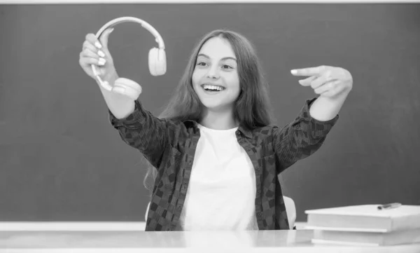 wireless headset device accessory. new technology. childhood development. child in modern earphones. online education. happy teen girl point finger on headphones. music lover. listen to music.