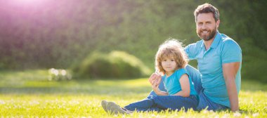 Açık yaz parkında baba ve oğulun bayrağı. Mutlu baba oğul portresi. Yaz parkında rahatla. Yeşil çimenler, aile sevgisi..
