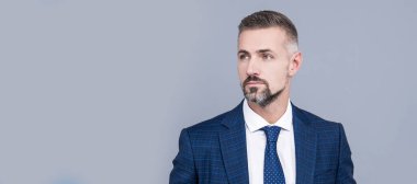 Olgun iş adamı resmi moda tarzı gri arka planda takım elbise giyer. İnsan yüzü portresi, kopyalama alanı olan pankart