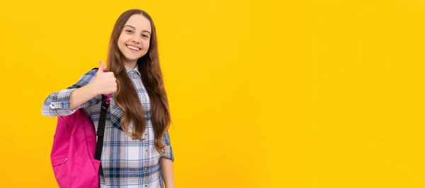 黄色い背景のリュック付きのチェッカーシャツの明るい子供 女子学生の肖像画 スタジオバナーヘッダー 学校の子供の顔 コピースペース — ストック写真