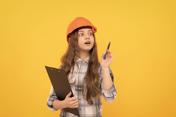 concentrated child worker wear hardhat hold clipboard. childhood development. happy labour day. future career. teen girl in helmet making notes. builder kid write in folder. building and construction.