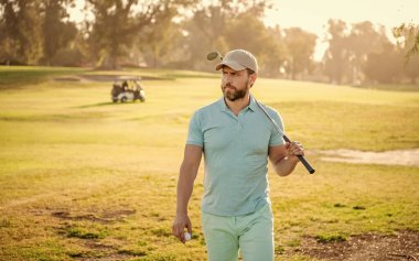 Golf oynayan bir adam yeşil çimlerde yürüyor..