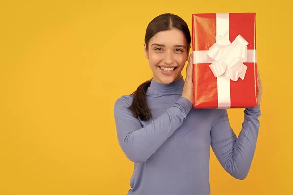 happy woman with red present box on yellow background, birthday.