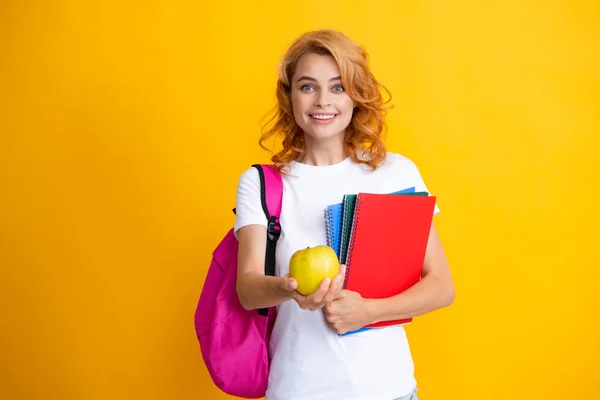 Excited redhead young woman student with backpack hold notebooks, isolated on yellow background studio Education in high school university college